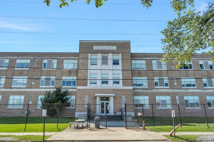 A large brick school building with a fence around it