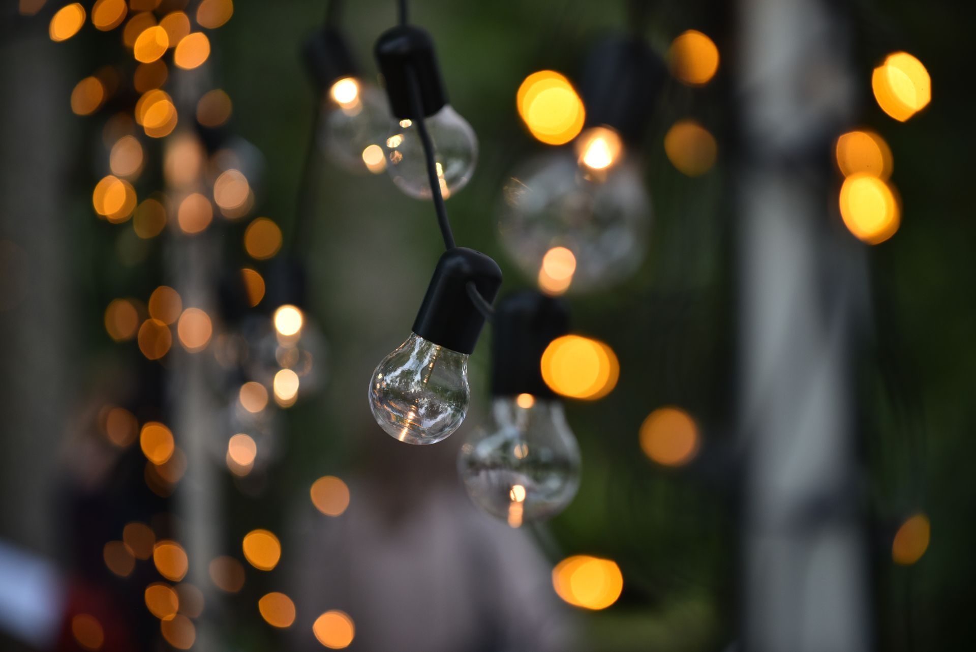 String lights with clear bulbs and blurred golden bokeh in a dark setting.