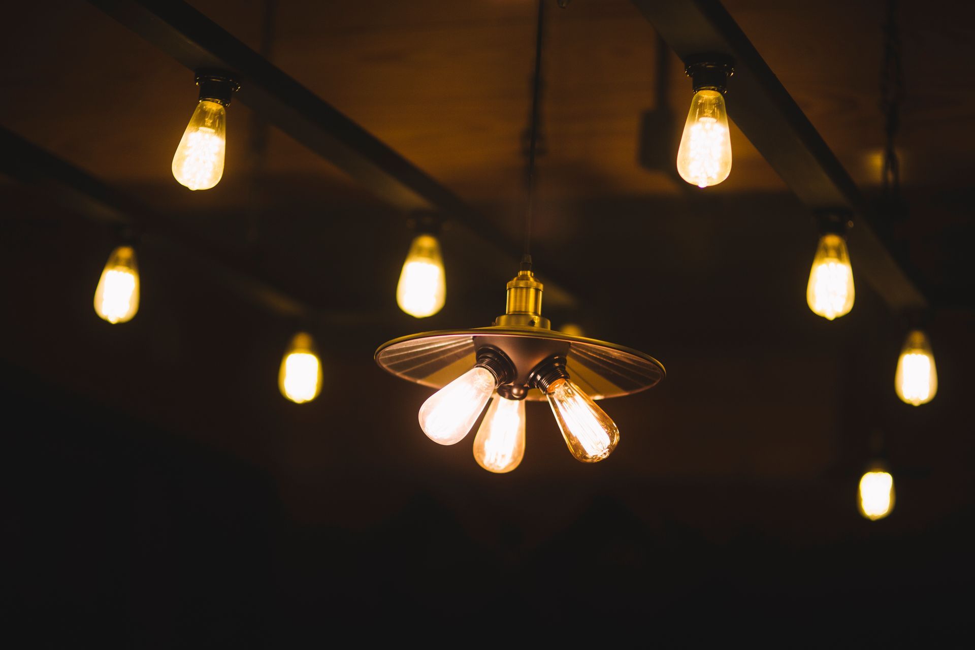 Warm-toned lightbulbs illuminate a dark ceiling, including a unique multi-bulb fixture.
