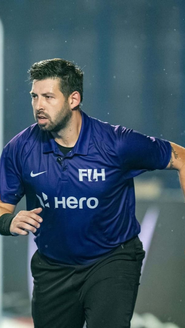 A man in a yellow shirt is standing next to a trophy.