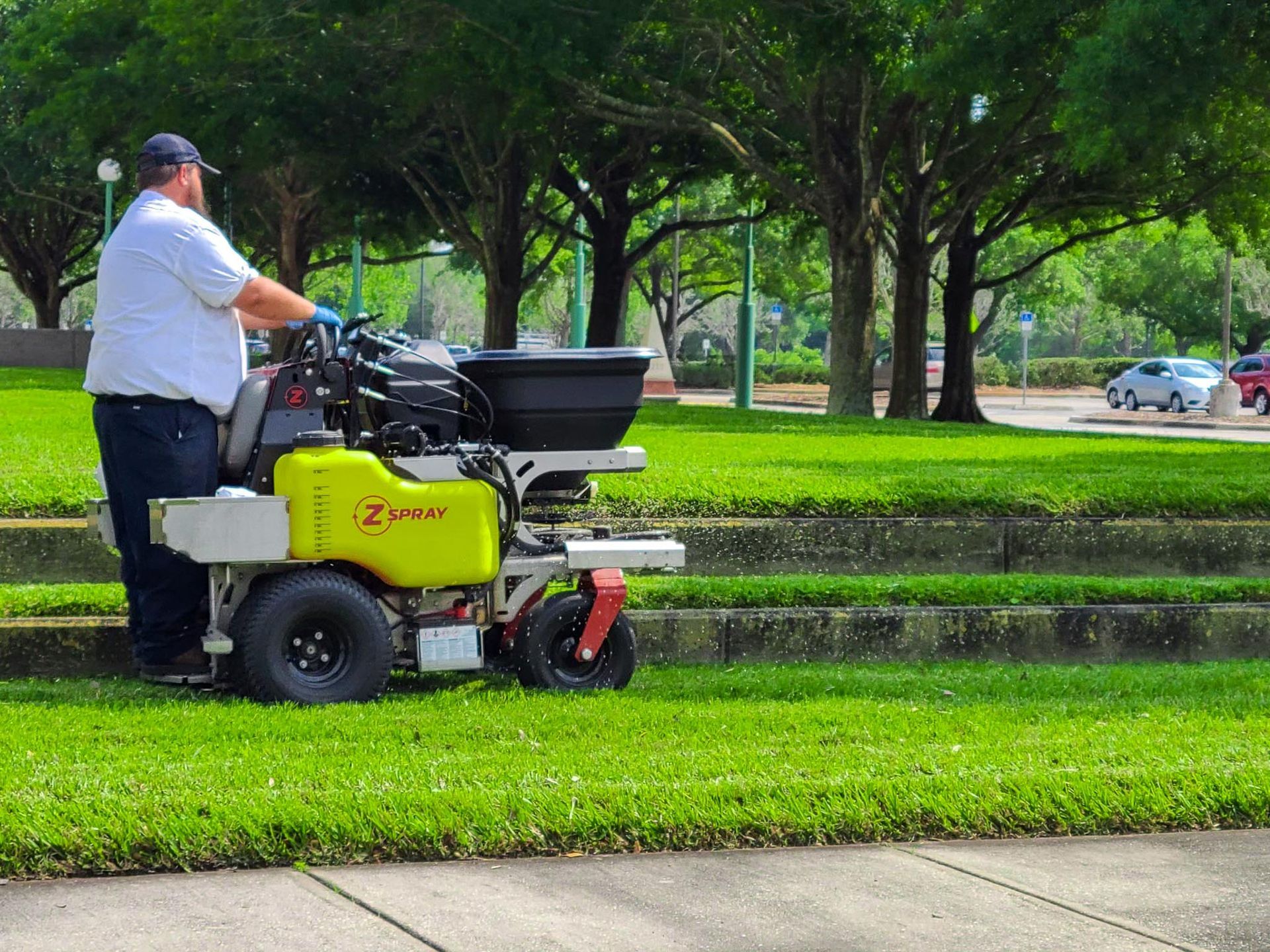 A man is riding a lawn mower in a park.