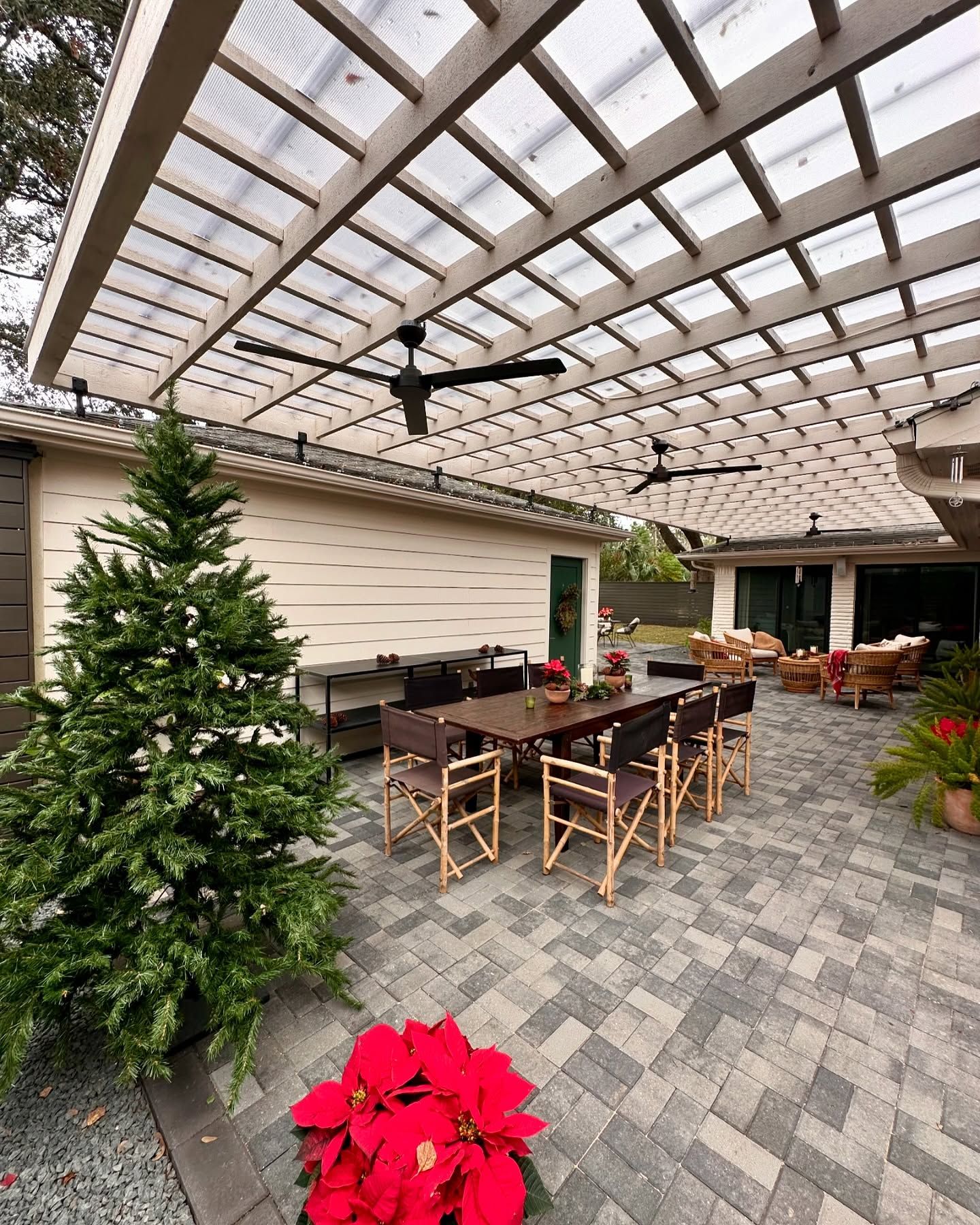 Outdoor dining area with a table, chairs, a pergola, and a Christmas tree.