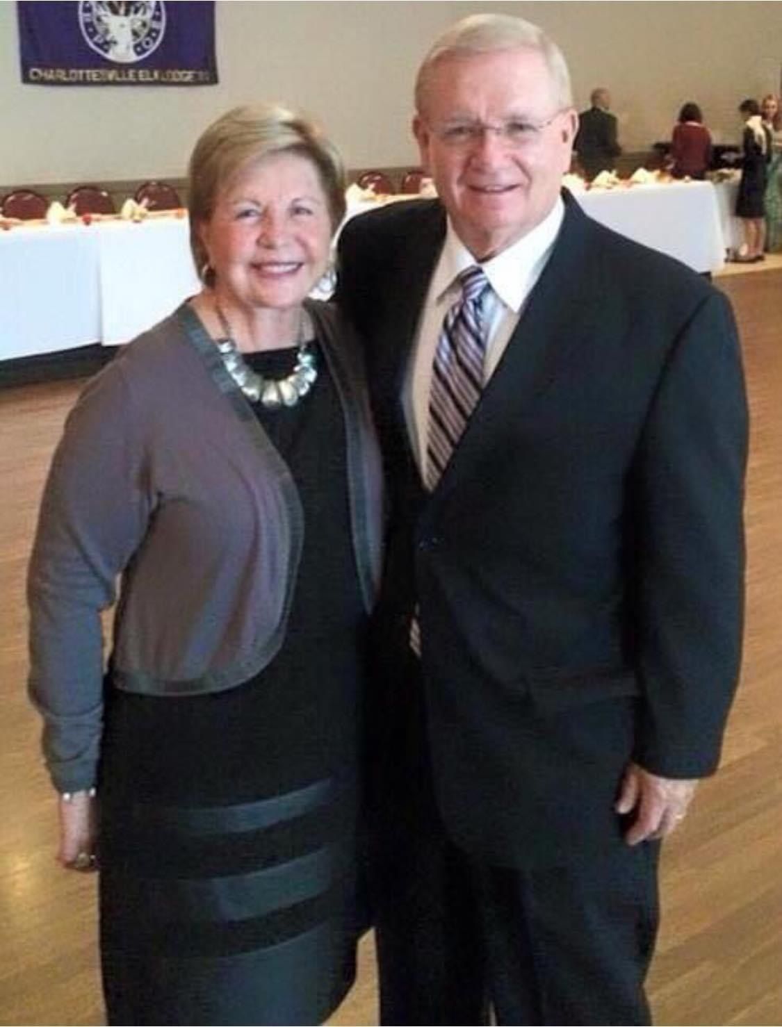 A man in a suit and tie poses with a woman in a black dress