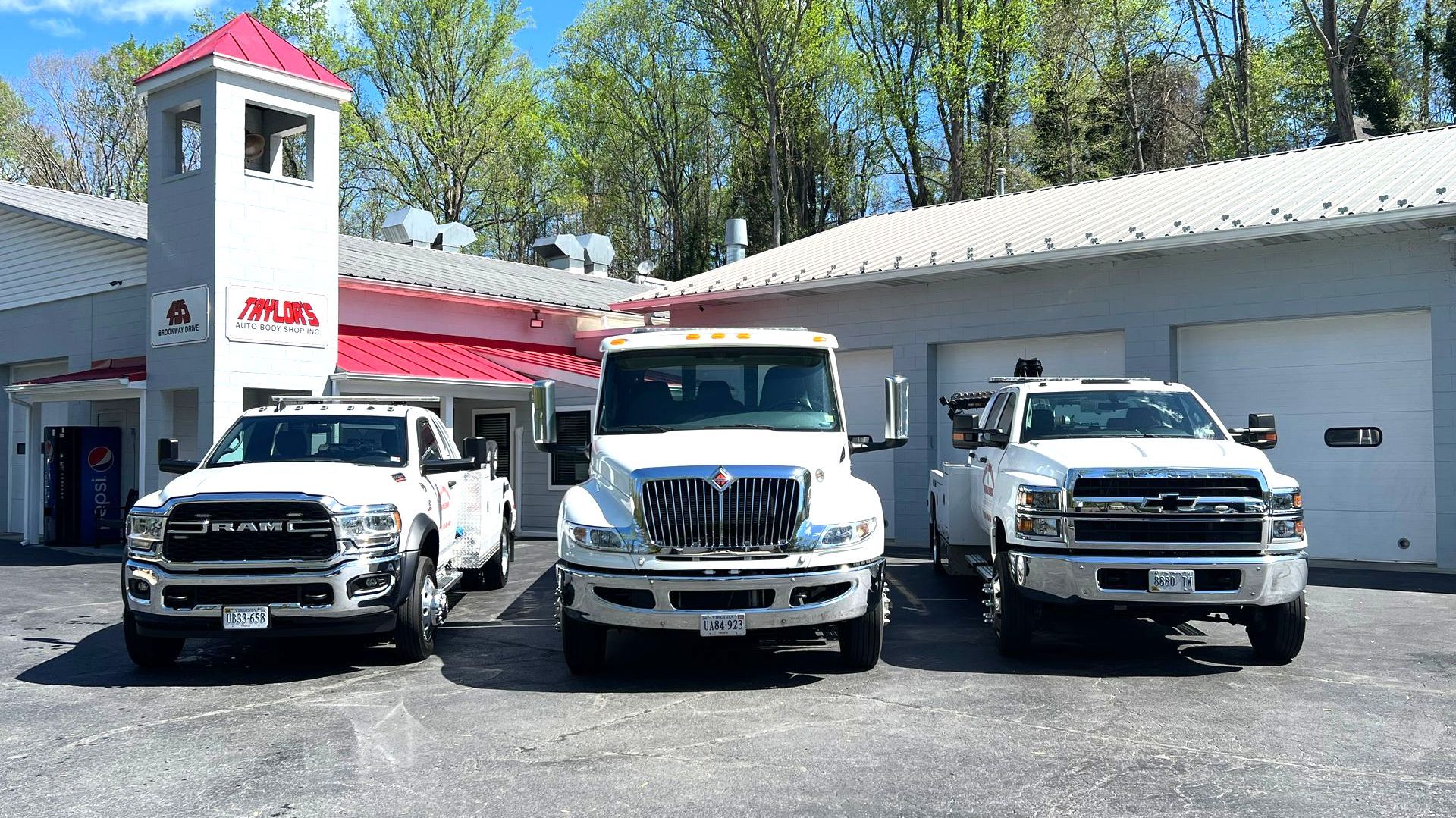 Three white trucks are parked in front of a building.