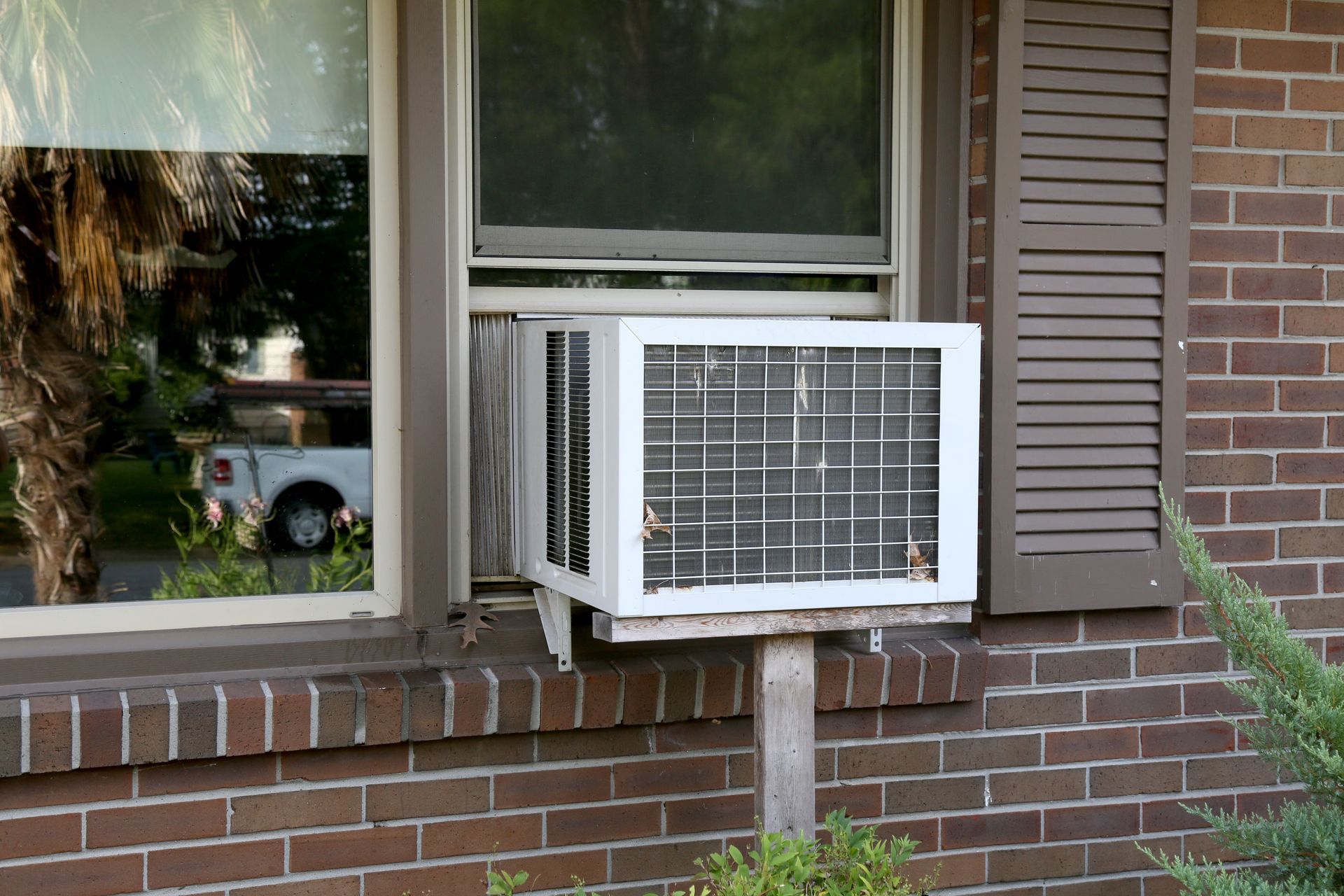 Window Air Conditioner Mounted Under a Brick House Window — Deltech HVACR in Georgetown, NSW