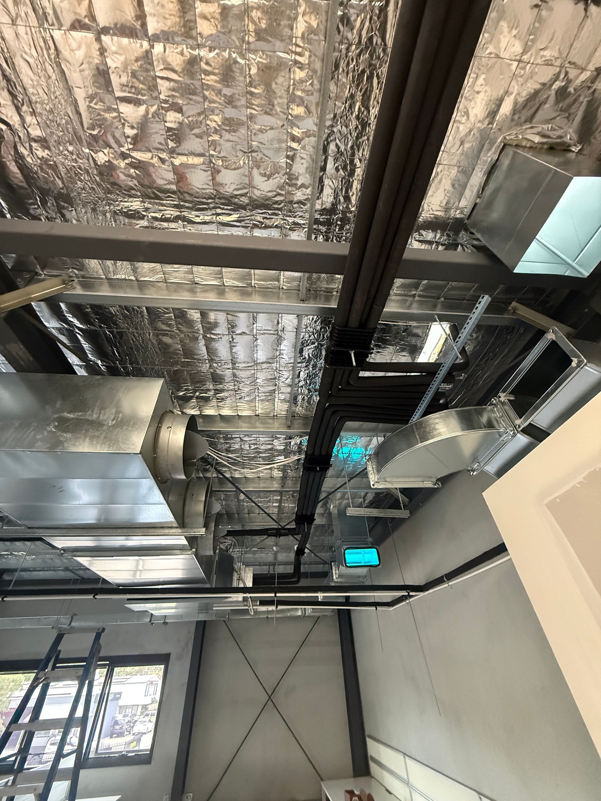 Exposed industrial ceiling with ducts, beams, and insulation in a building interior — Deltech HVACR in Georgetown, NSW