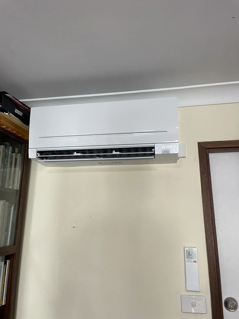 Wall-mounted White Air Conditioner Above a Beige Wall With a Window — Deltech HVACR in Port Stephens, NSW