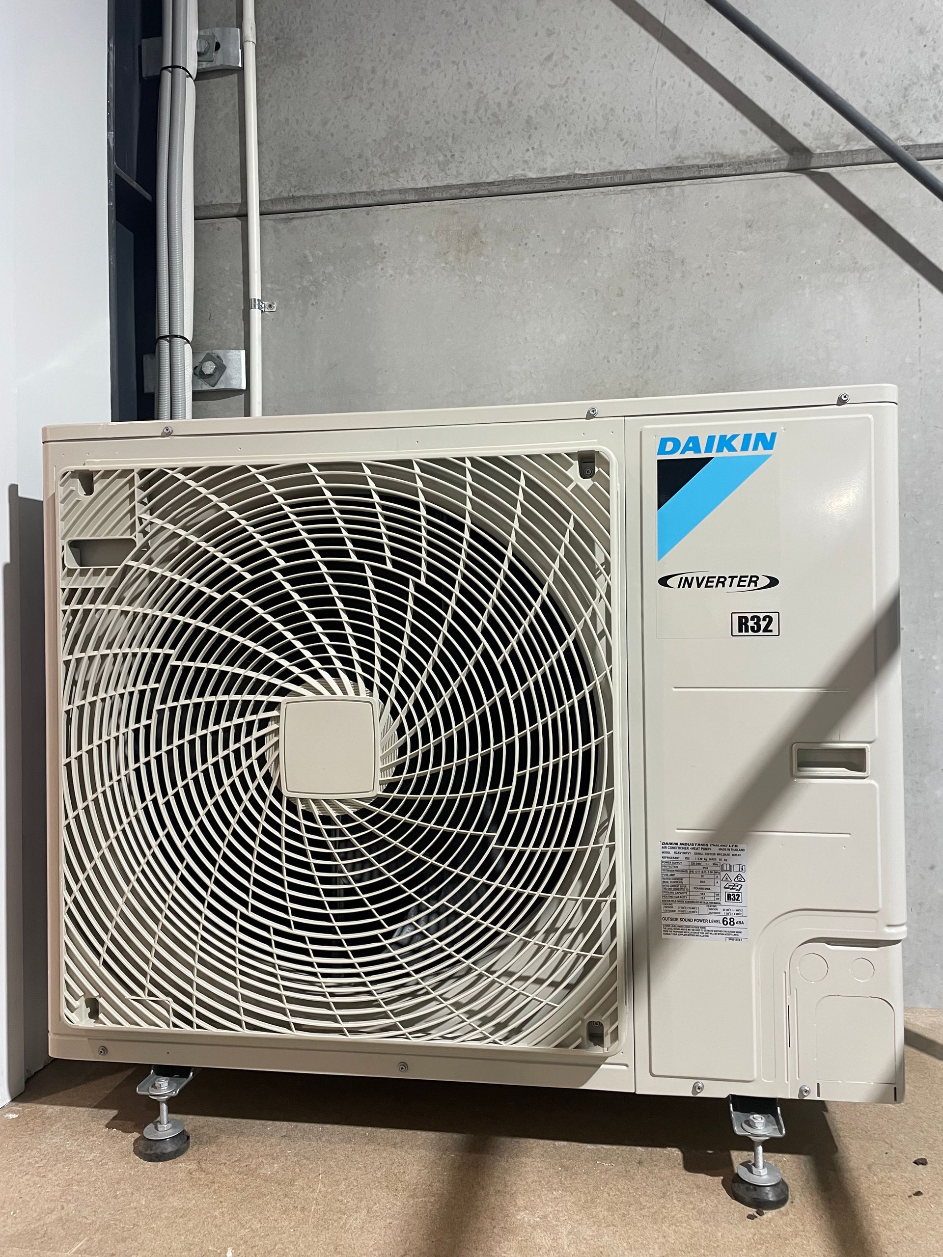 Outdoor Daikin HVAC unit with large fan grille, mounted on brackets against a wall indoors — Deltech HVACR in Georgetown, NSW