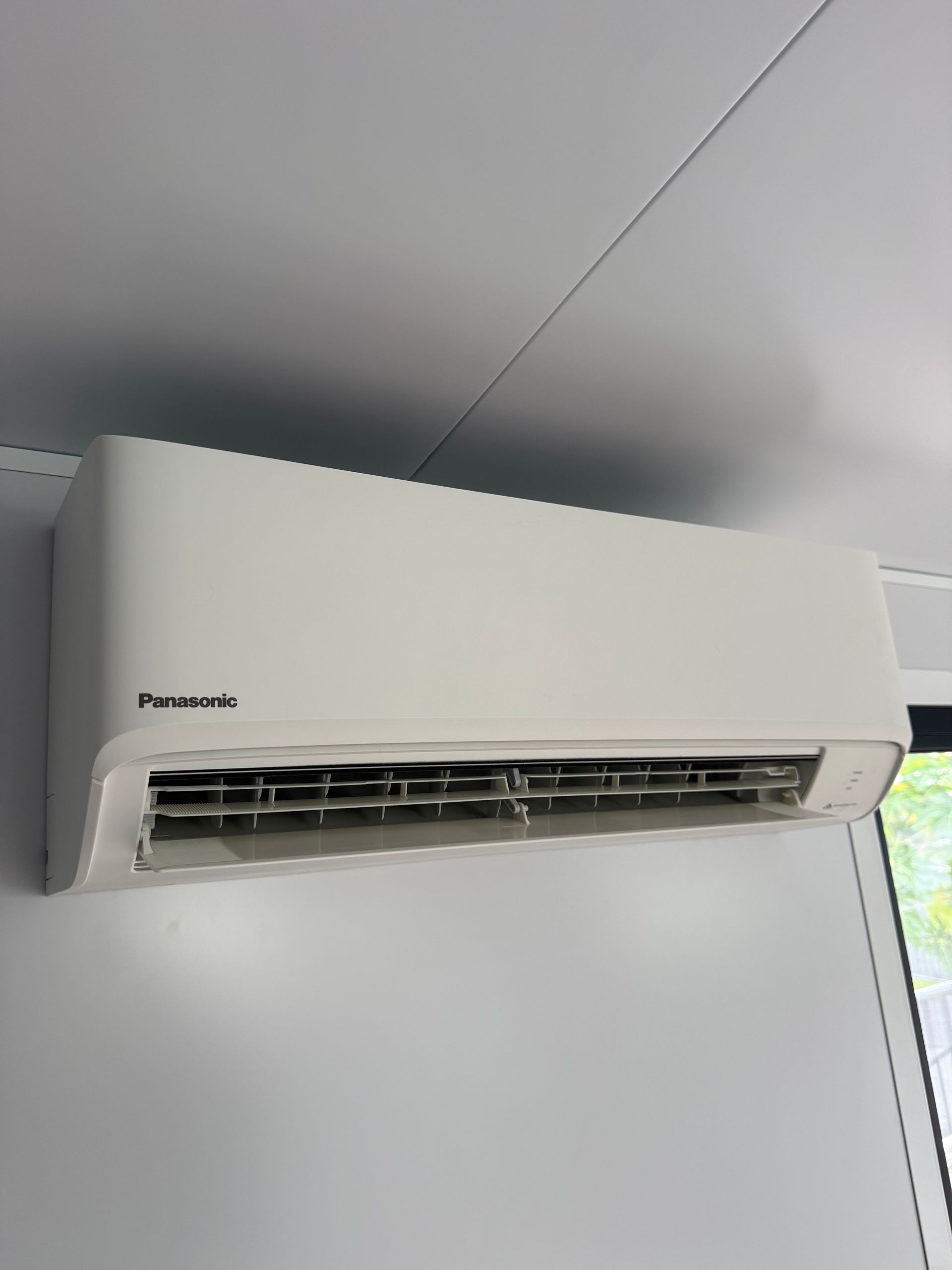 White wall-mounted air conditioner near the ceiling in a room — Deltech HVACR in Georgetown, NSW
