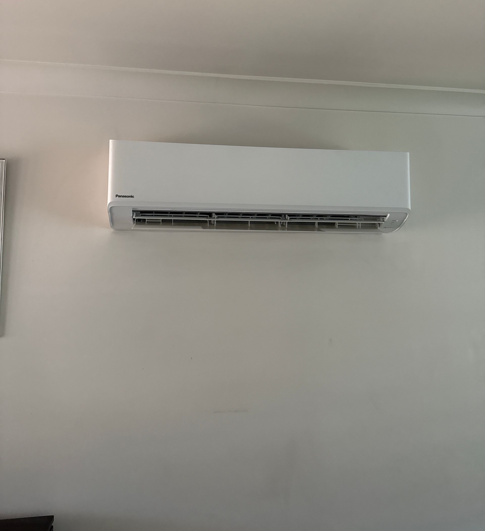 White Hisense Outdoor Air Conditioner Unit Beside a Corrugated Metal Wall on Gravel — Deltech HVACR in Maitland, NSW