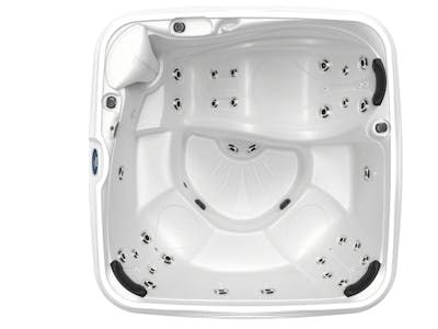 Overhead view of a white, empty hot tub with multiple jet nozzles and seating areas.