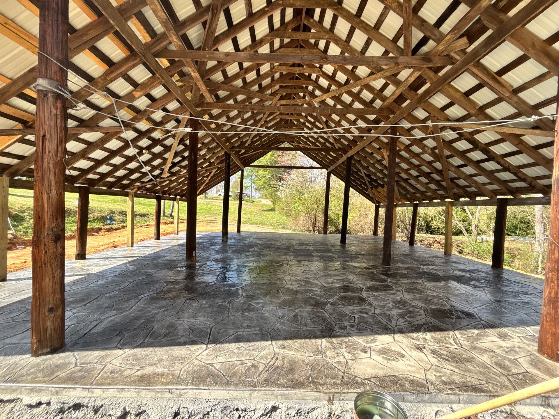 Wooden pavilion with a concrete floor, set outdoors.