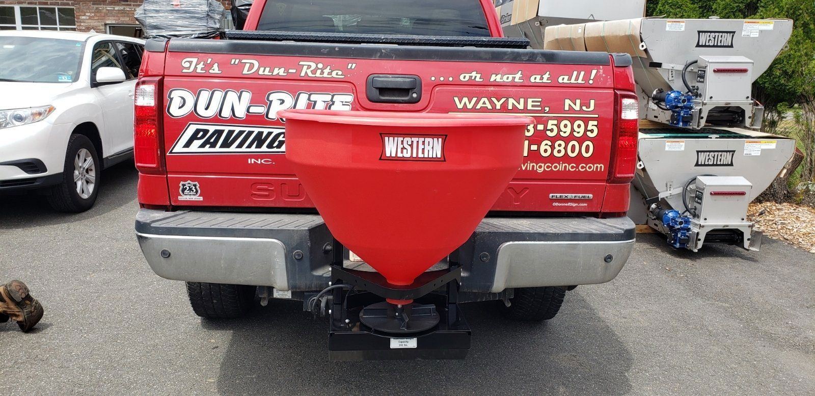 Red pickup truck with a red salt spreader attached