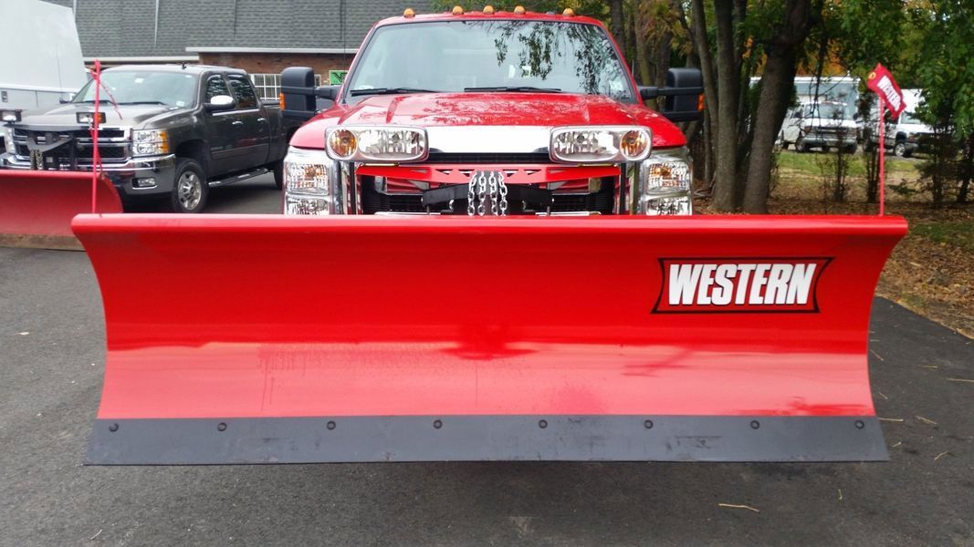 Red Western snow plow attached to the front of a red pickup truck, ready for winter.