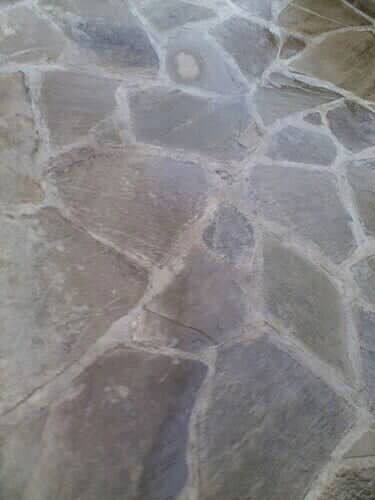 Stone floor with irregular, multi-faceted pieces in shades of gray and brown, with white grout lines.
