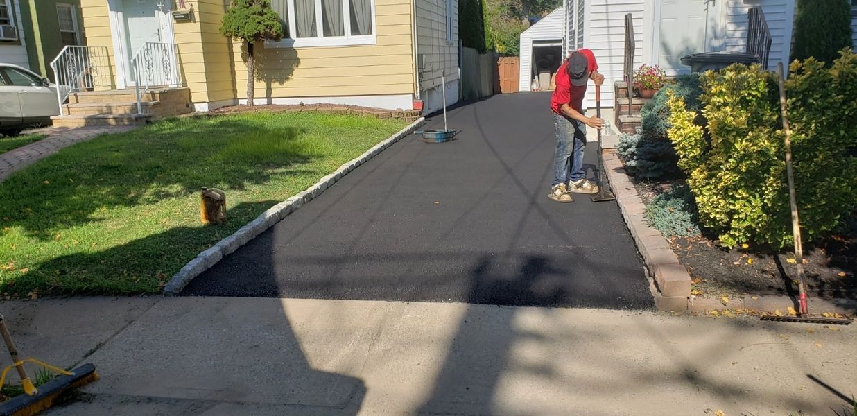 Person raking new black asphalt driveway. 