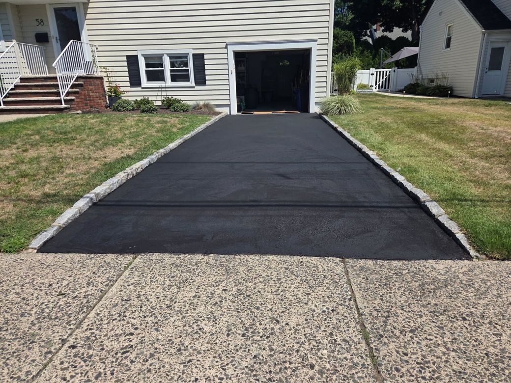 Asphalt paving: workers with truck laying blacktop on a driveway; suburban setting.