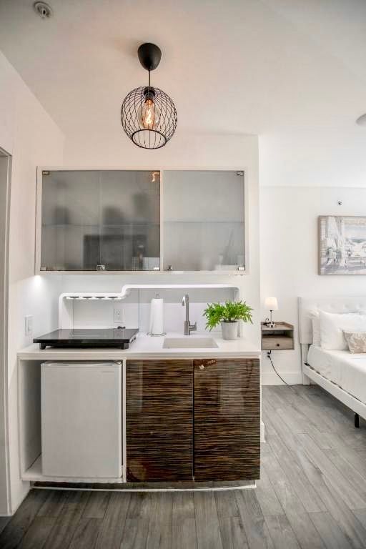 Small kitchenette with white cabinets, a brown wood-grain lower cabinet, and a small refrigerator.