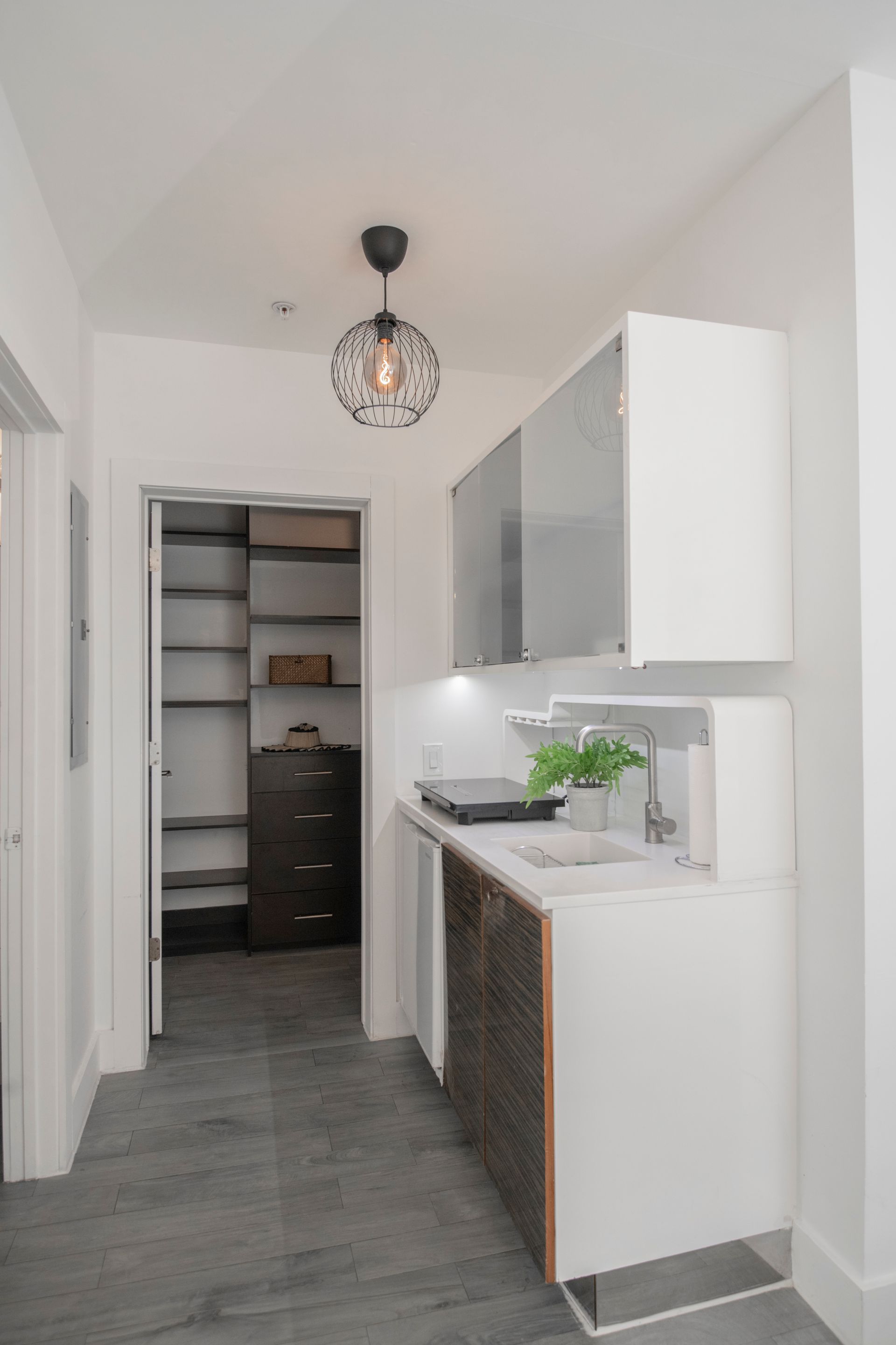 Modern white laundry room with a sink, cabinets, and open pantry.