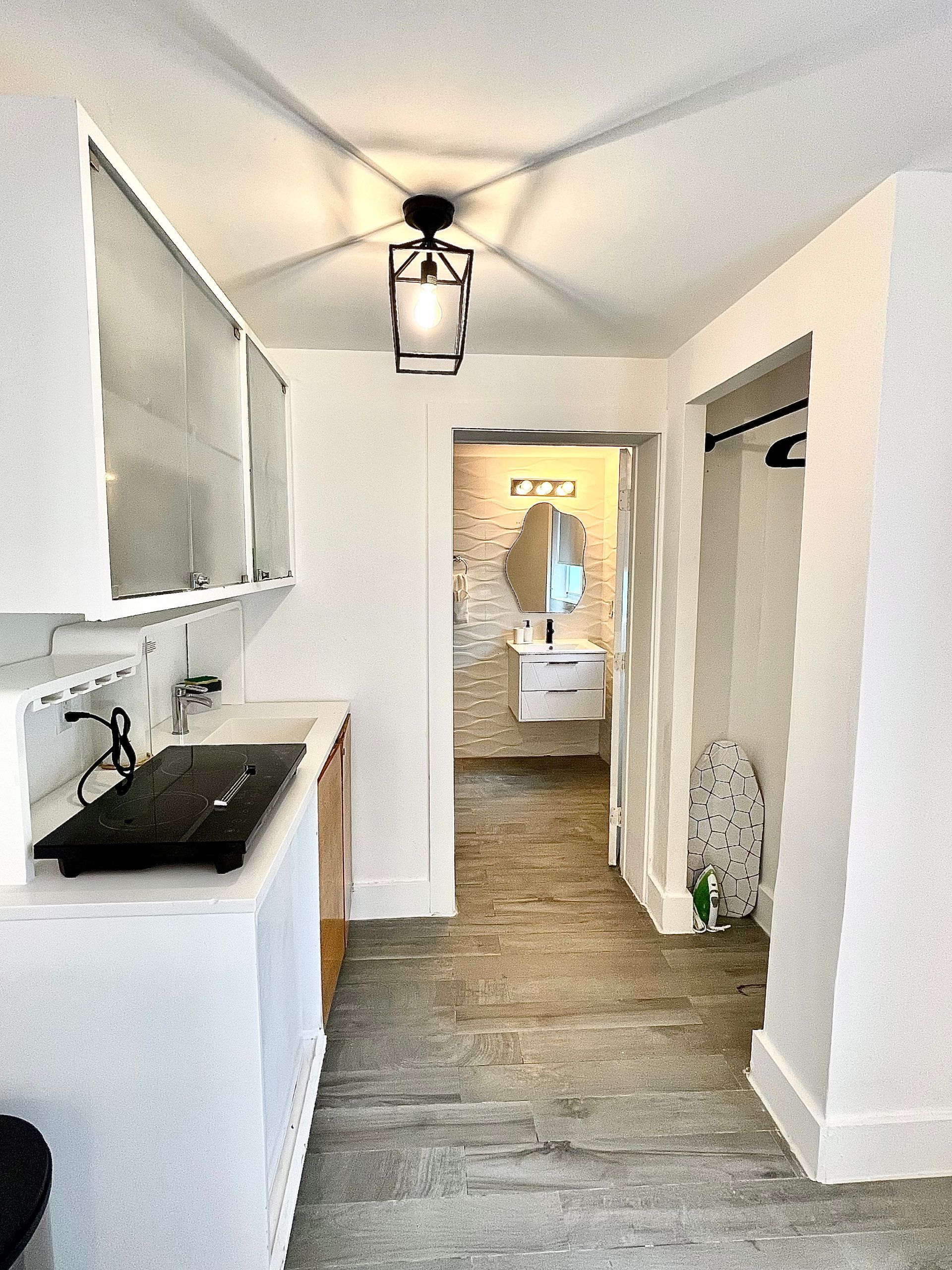 Narrow hallway with kitchen on left, bathroom straight ahead; neutral tones.