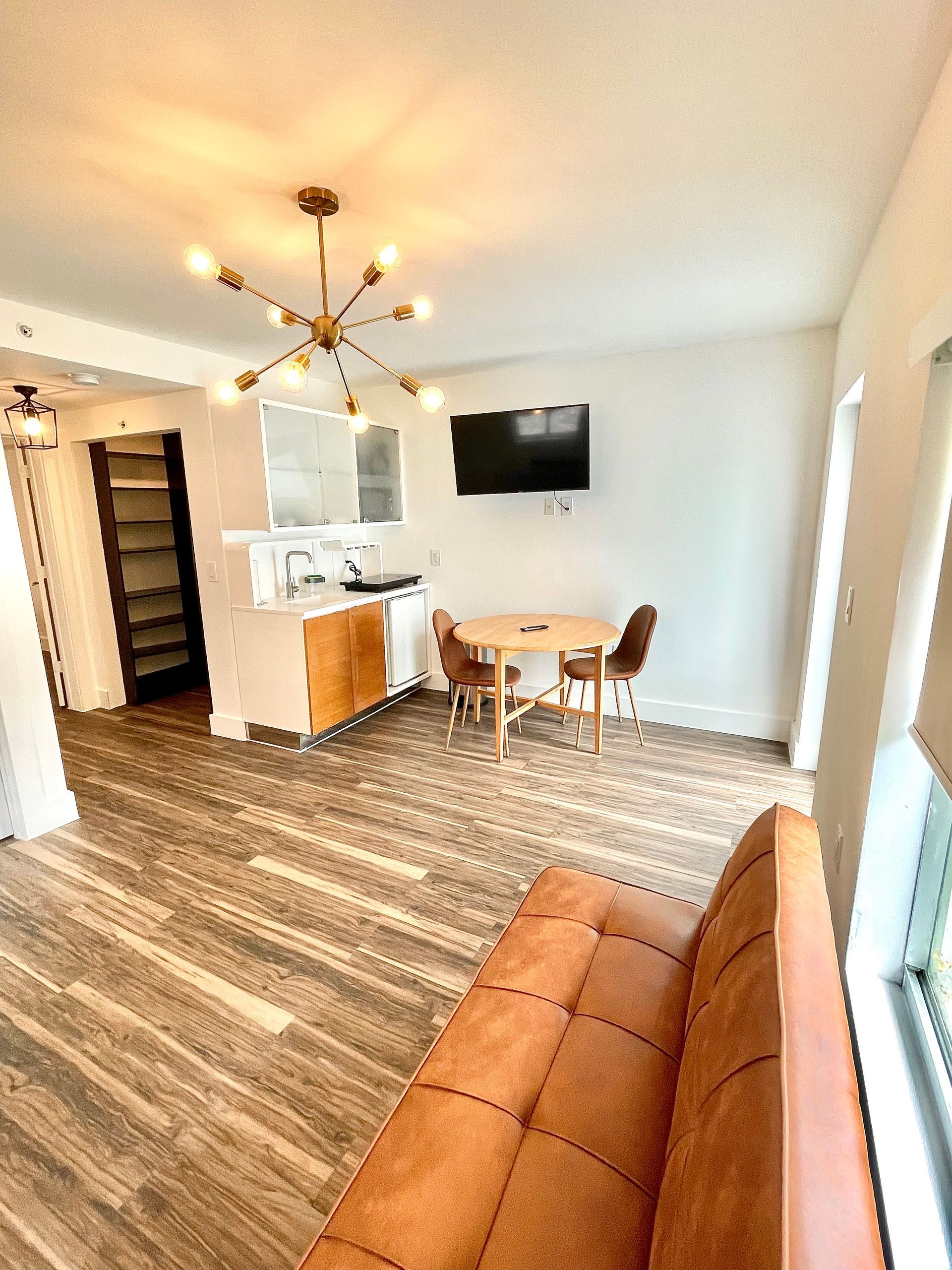 Cozy living space with dining area, kitchen, and sofa, light brown and white color scheme.