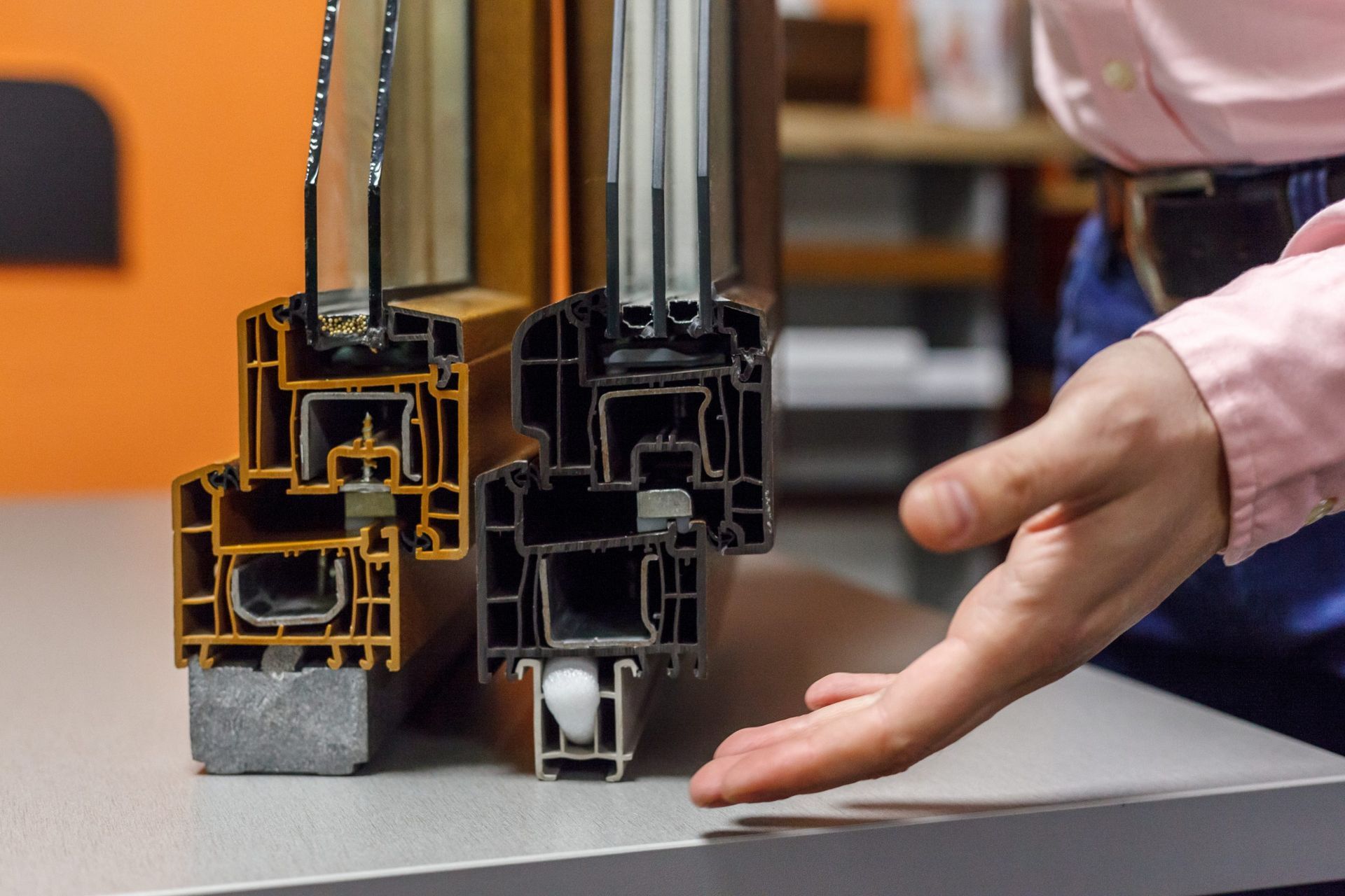 Why Window Tint Could Be A Better Option Than Replacement Windows For Your Home Cross-section view of two window frames, one gold and one black, with a person's hand gesturing toward them.