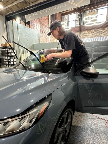 A person is cleaning a car with a blue sponge.