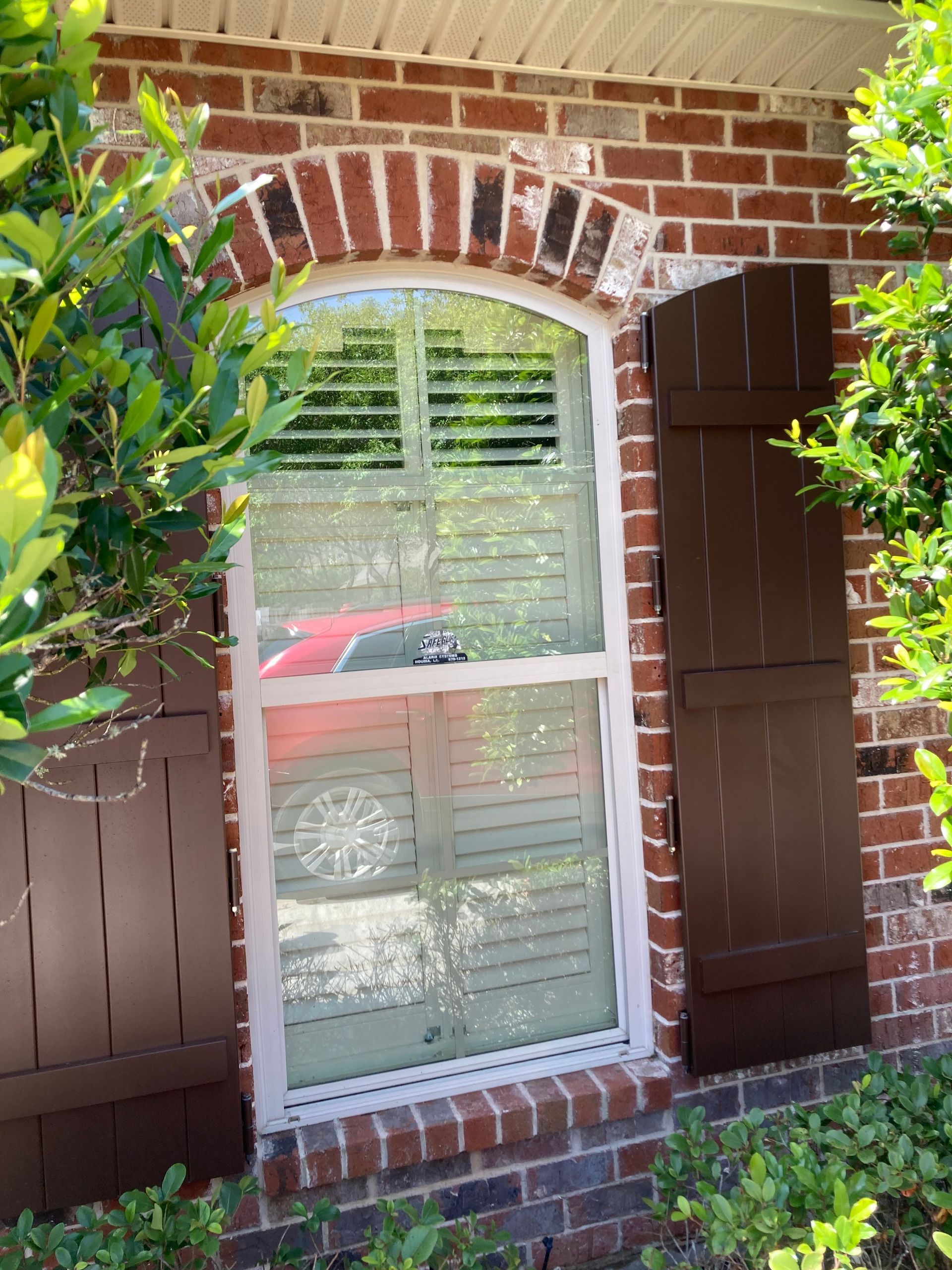 A brick building with a window and brown shutters