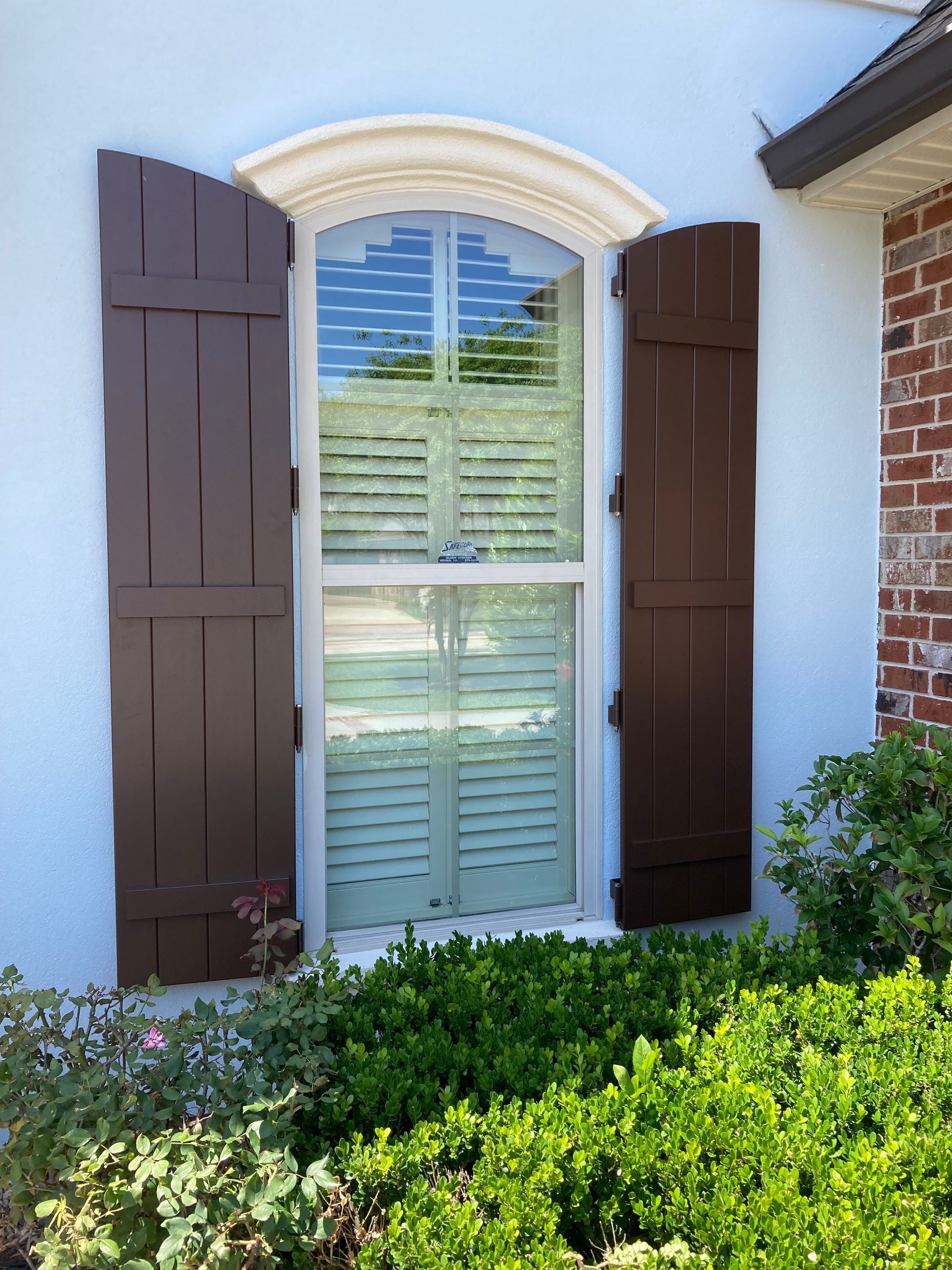A window with brown shutters on a blue house