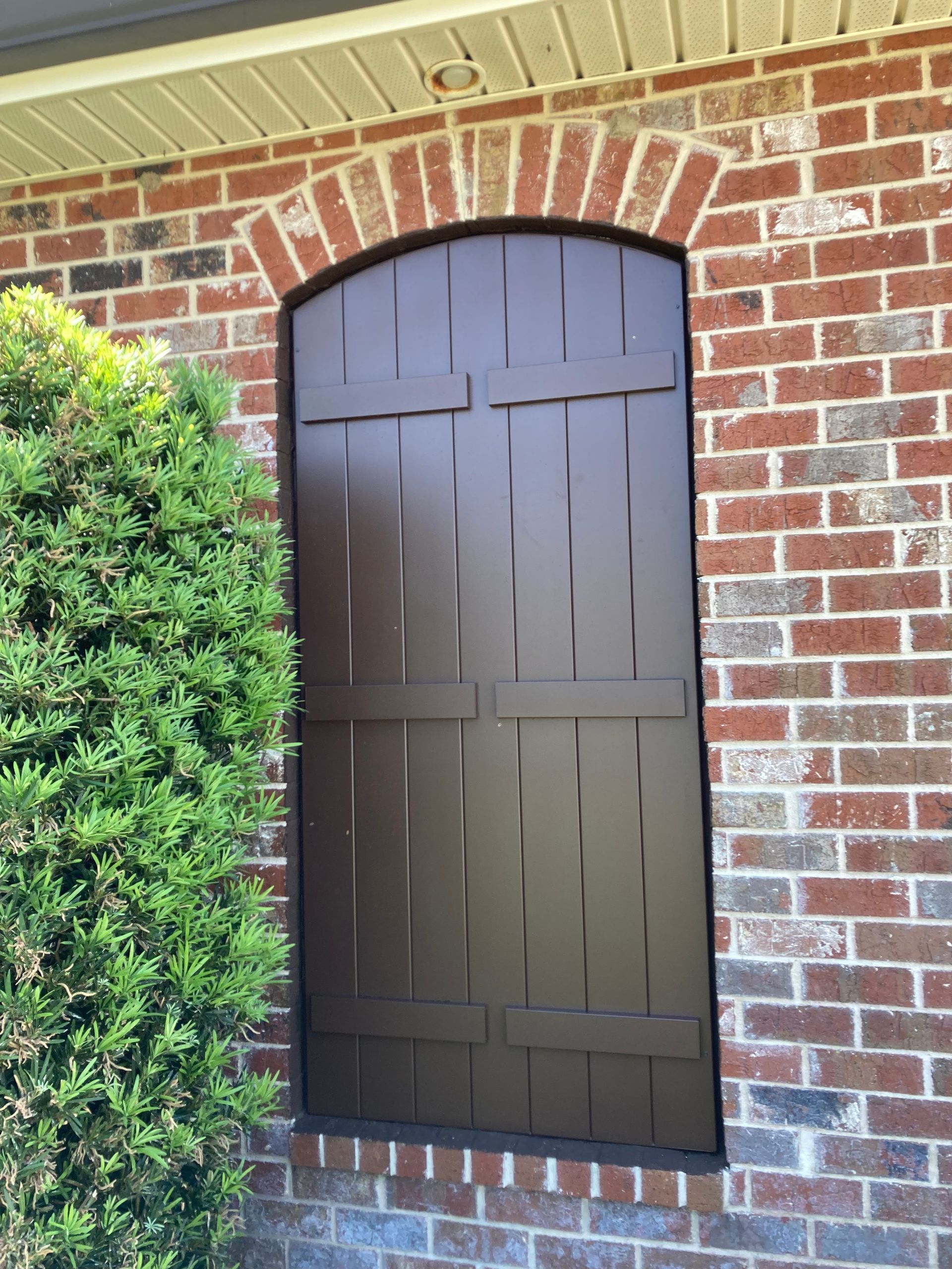 A brick building with a window and brown shutters
