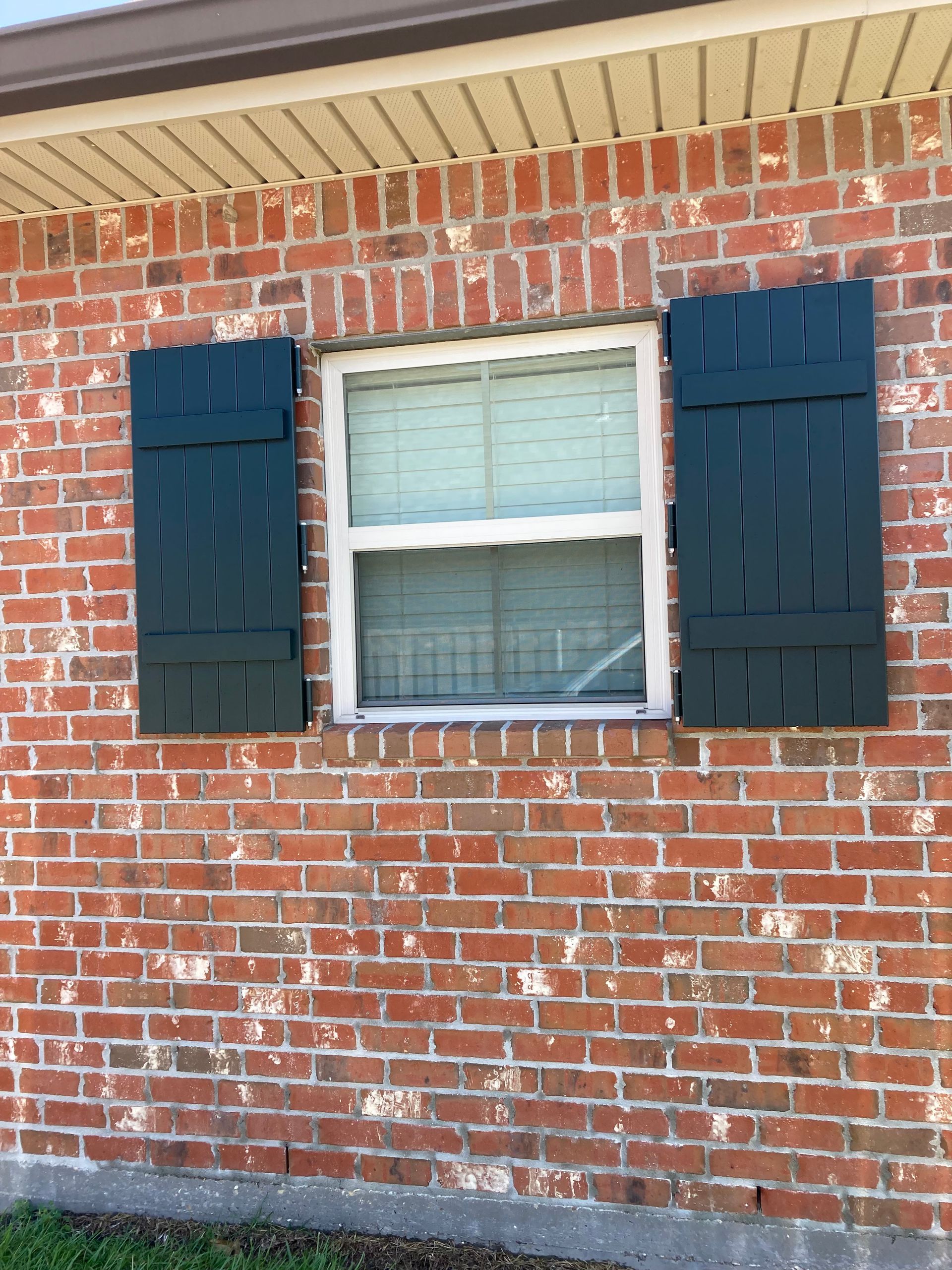 A brick house with black shutters on the windows