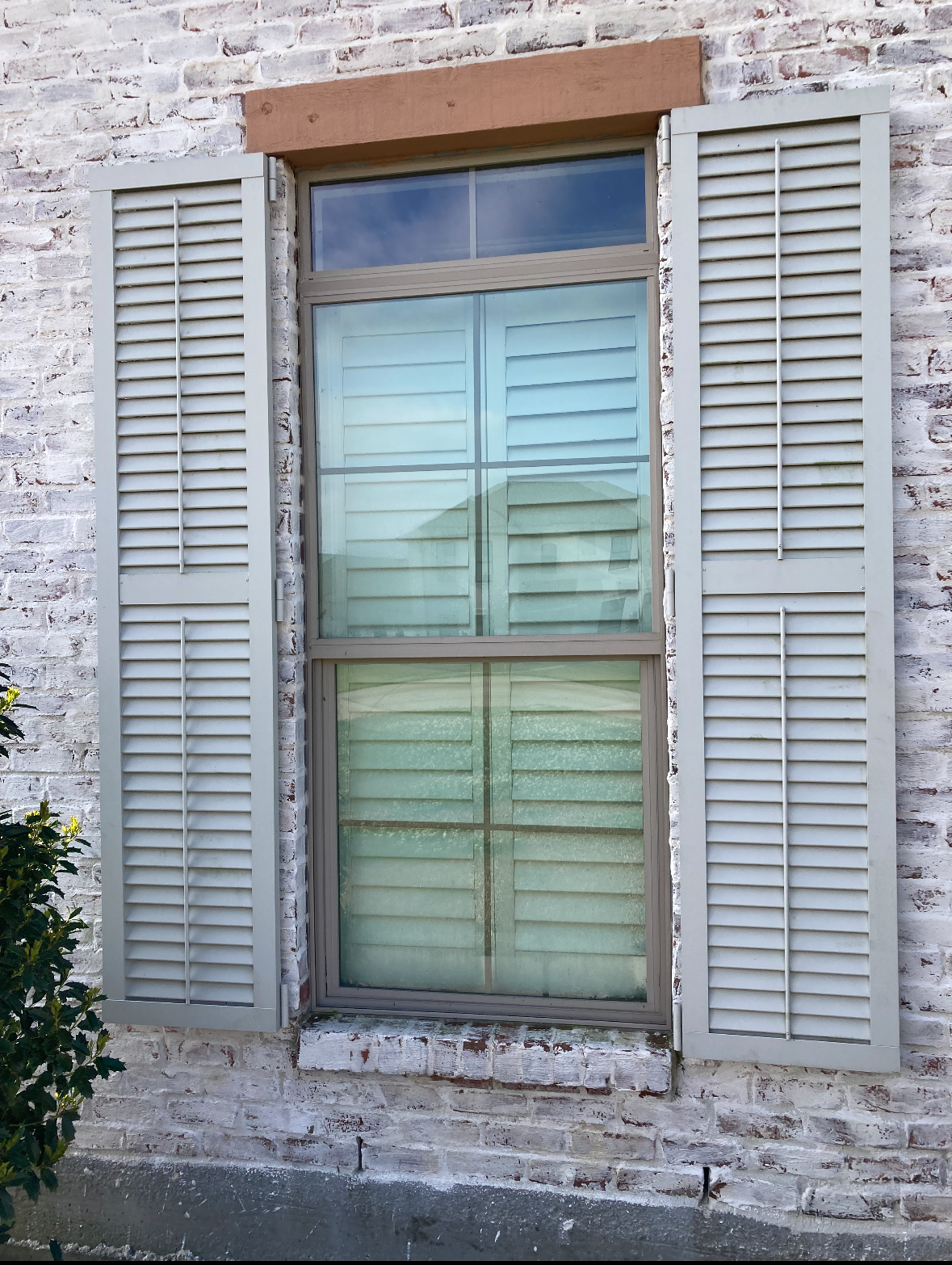 A window with shutters on a white brick wall