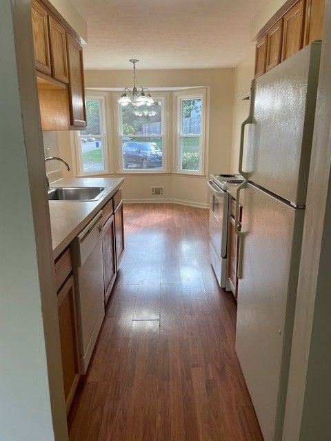 Small bathroom with white tub, toilet, vanity and tan walls.
