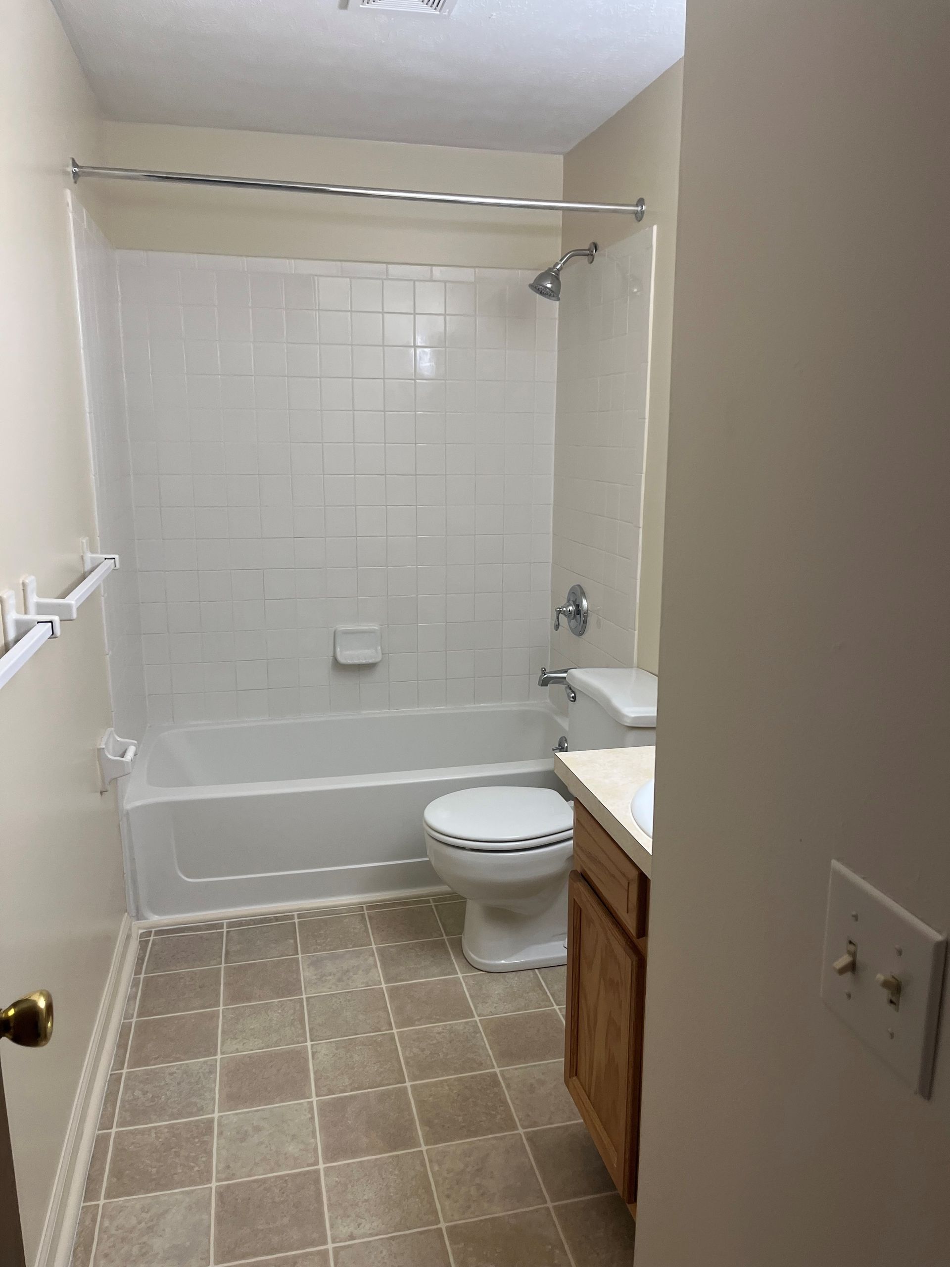Playground with wooden structure, surrounded by wood chips, near tan apartment buildings.