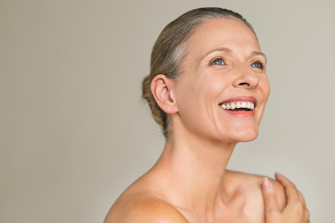 A woman is smiling and looking up at the sky.