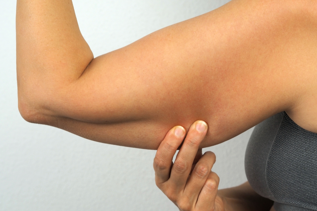 A woman is holding her arm with her hand.