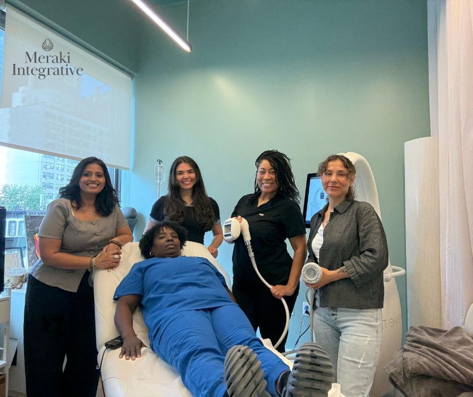 Four people in a treatment room: One reclined, three standing. One person holds a device.
