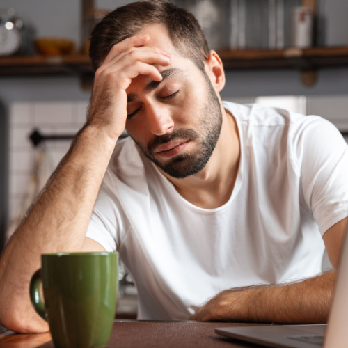 A man is sitting at a table with his head in his hand.