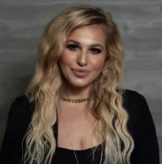 A woman with long blonde hair is wearing a choker and a black top.