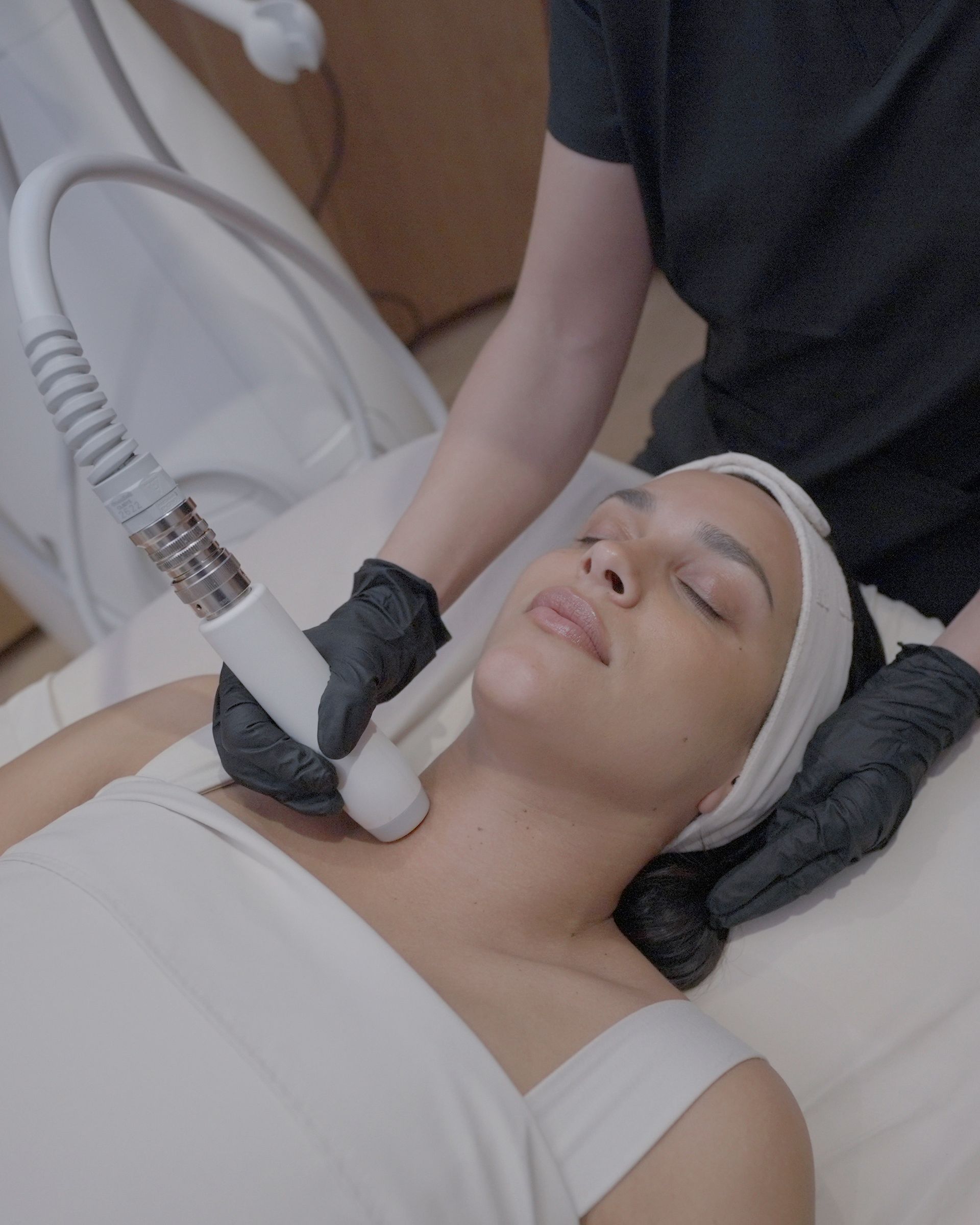 A woman is laying on a bed getting a T-shape 2 facial treatment