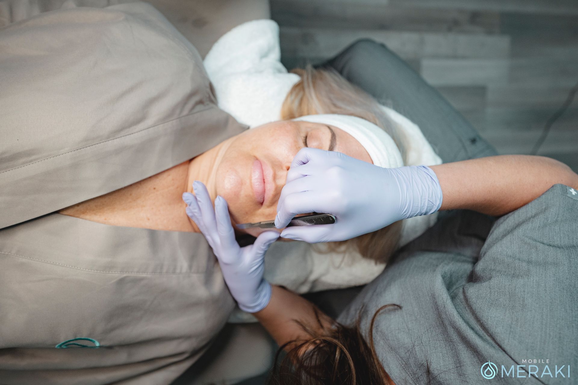 A woman is laying on a bed getting a facial treatment from Meraki Integrative Wellness and Medspa