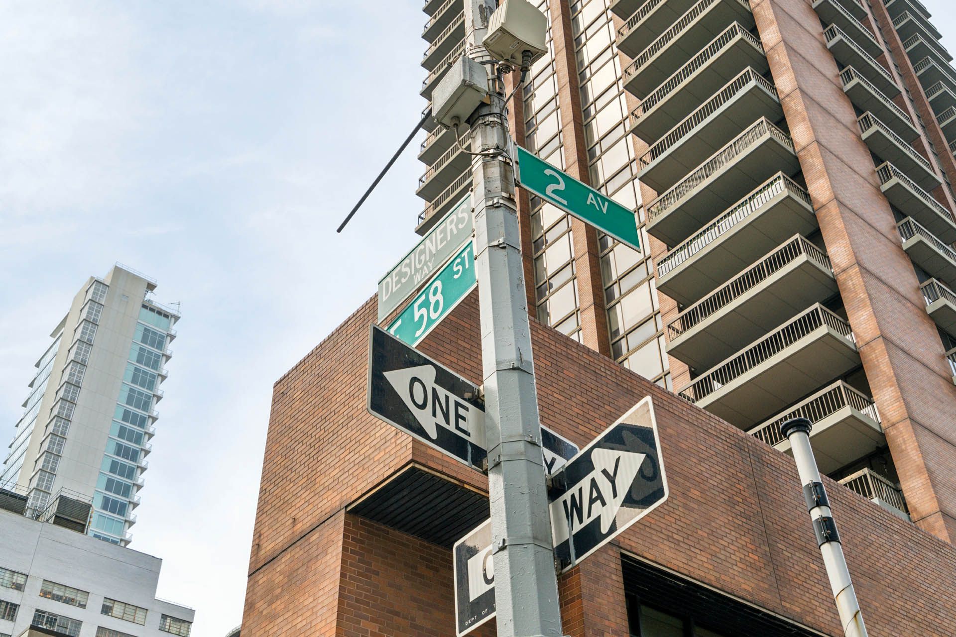 A one way sign is on a pole in front of a building