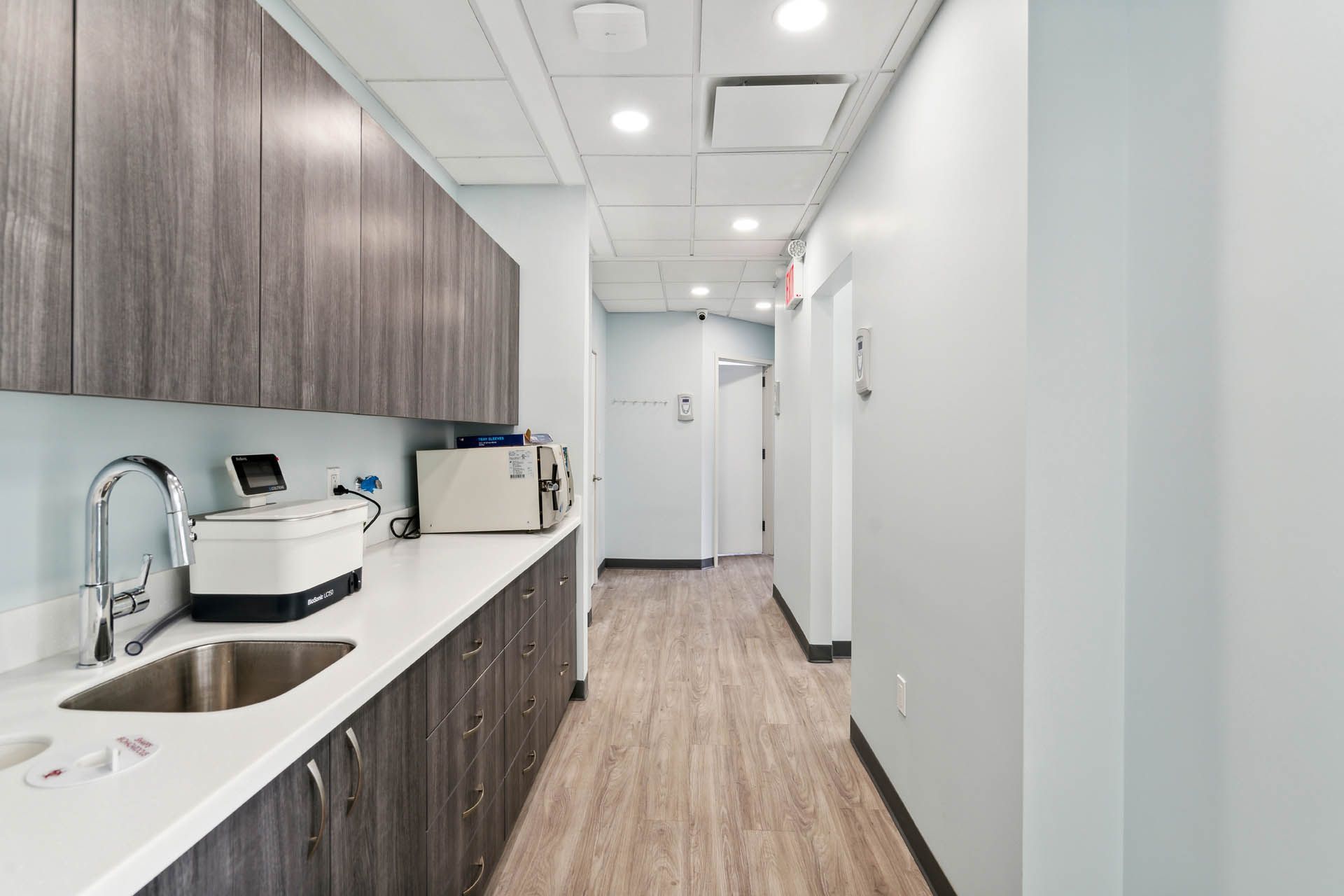 A kitchen with a sink and a microwave in a hallway.