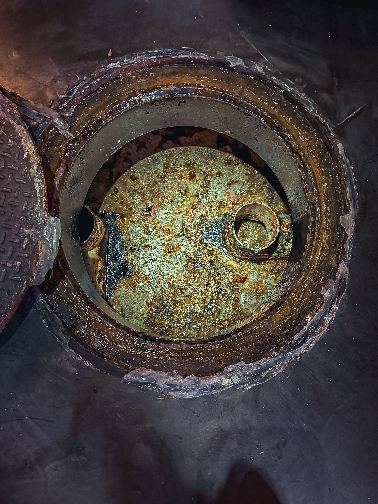 A close up of a manhole cover with a hole in it.