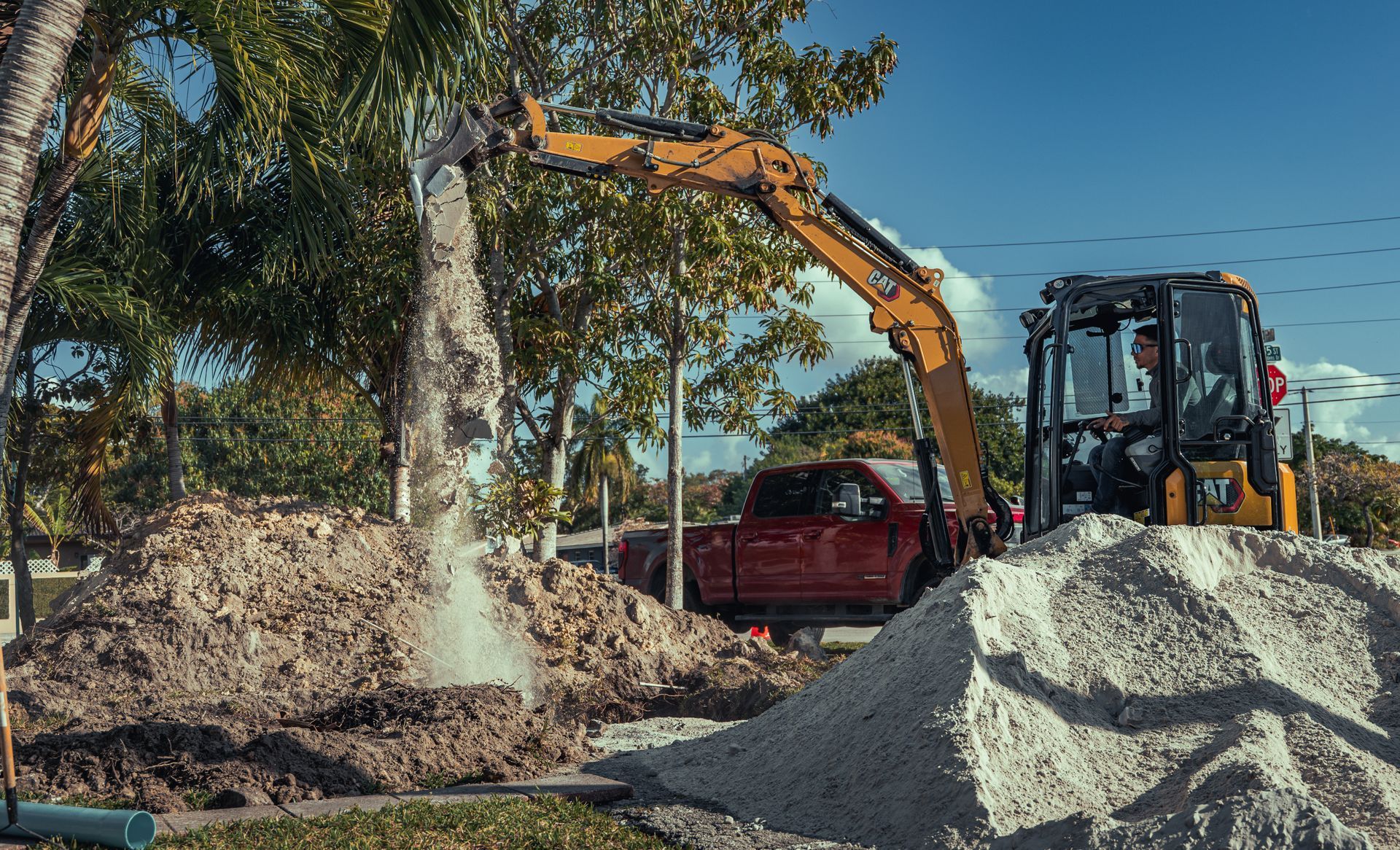 A bulldozer is digging a hole in the ground next to a pile of dirt.