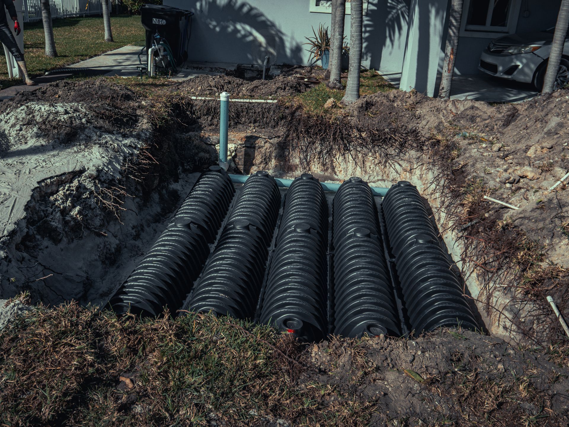 A septic system is being installed in the dirt in front of a house.