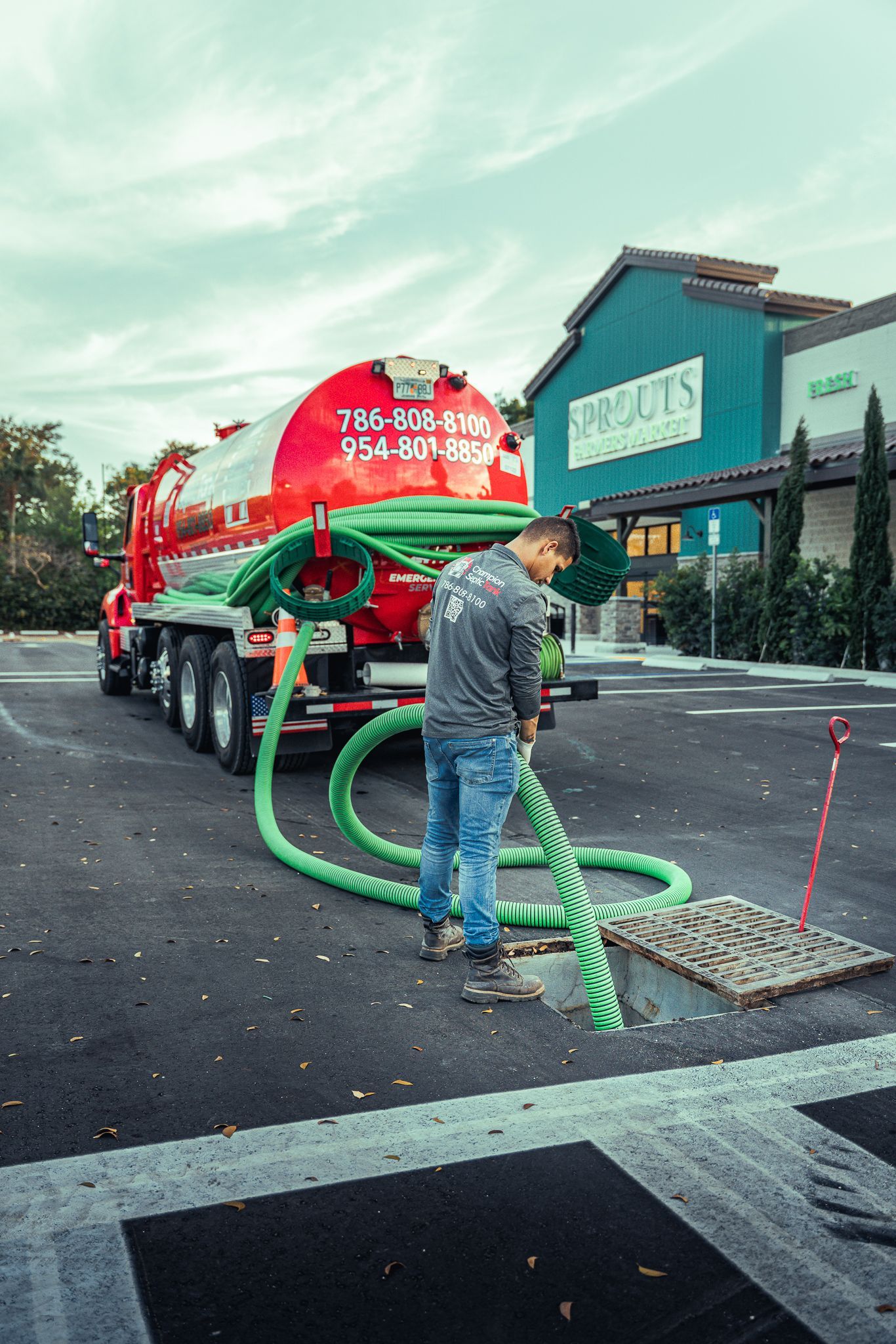 A man is pumping water from a septic tank into a manhole cover.