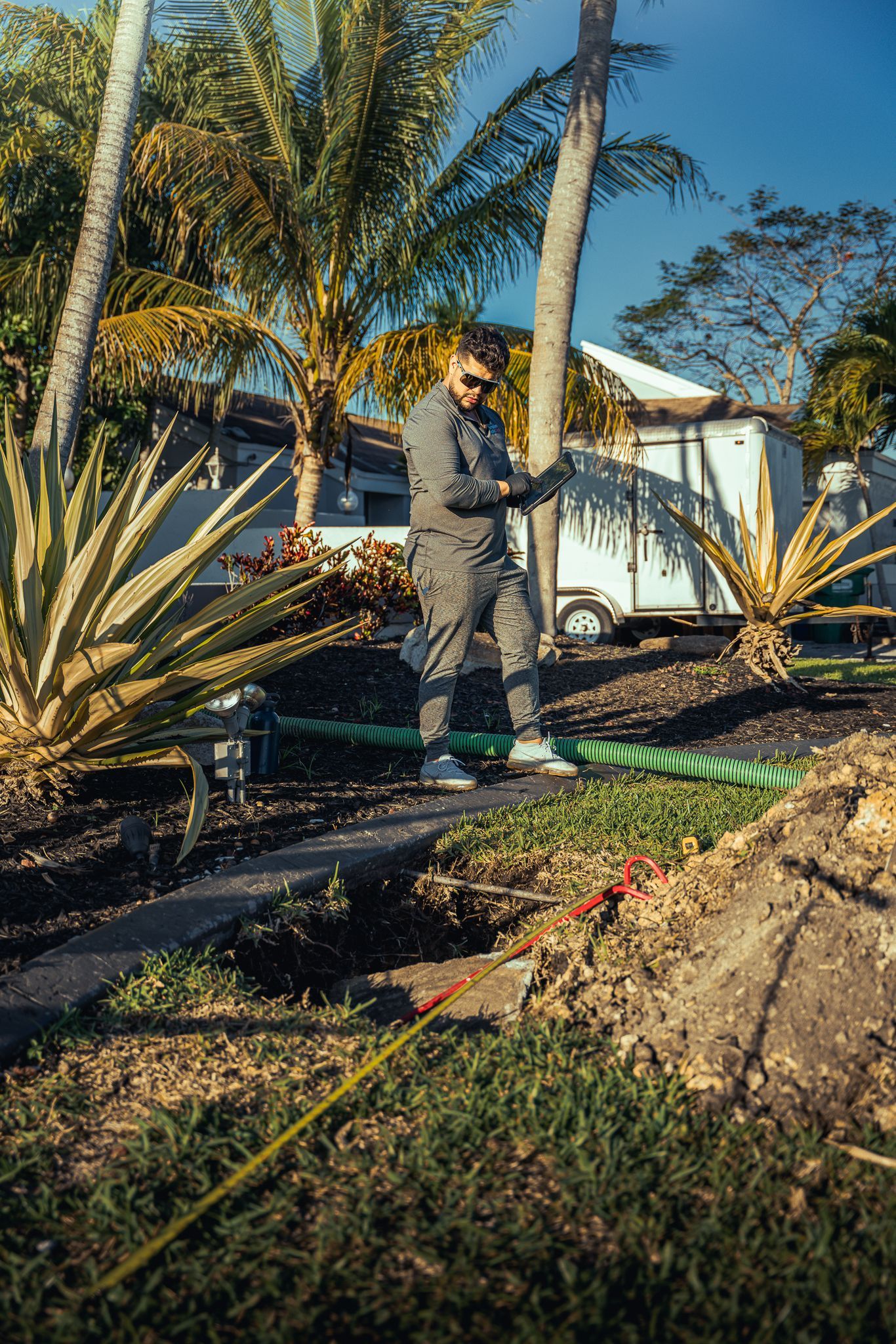 A man is standing next to a hose in a garden.