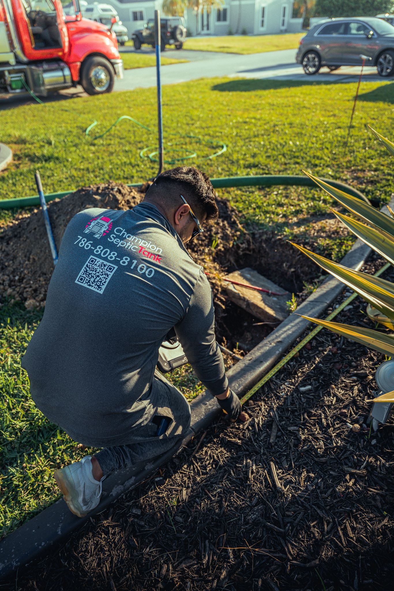 A man is kneeling down in the dirt next to a truck.