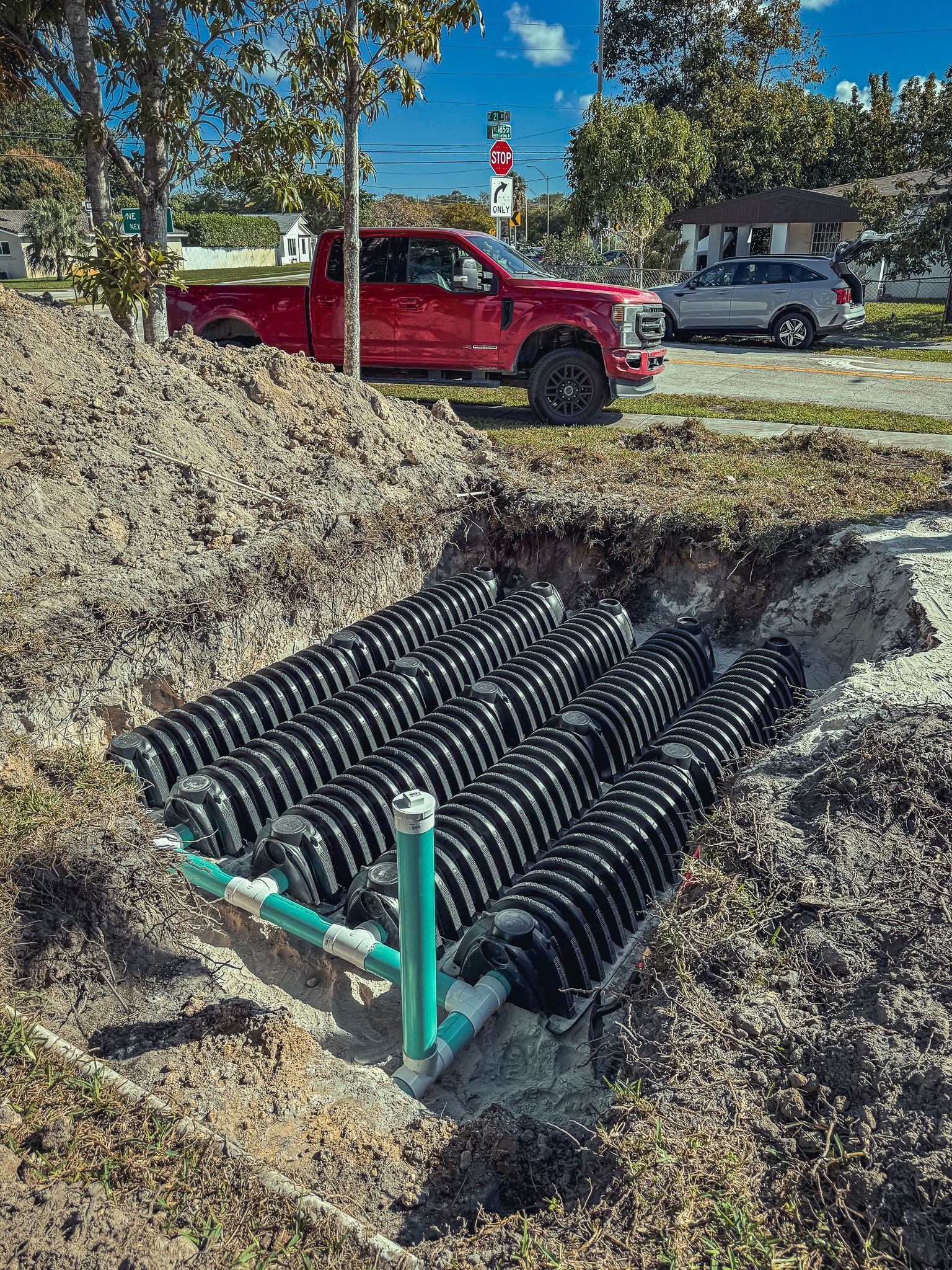 A red truck is parked in the dirt next to a septic tank.